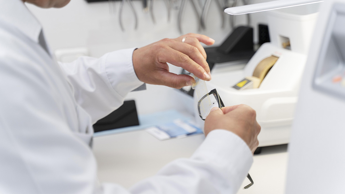 Un opticien en train d'assembler des lunettes dans un laboratoire avec de l'équipement médical.